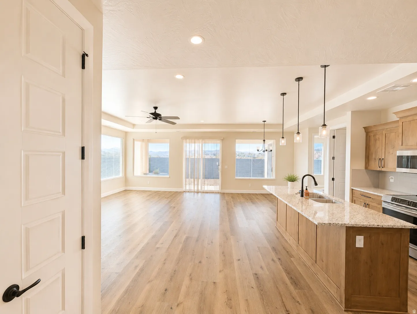 Expansive open-concept living area featuring wood-finish flooring, recessed lighting, and a ceiling fan