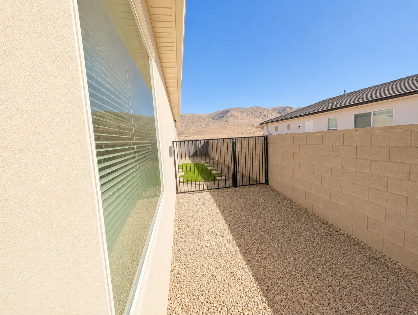 Side yard featuring pea gravel ground cover, a large privacy window with blinds, and a durable block wall