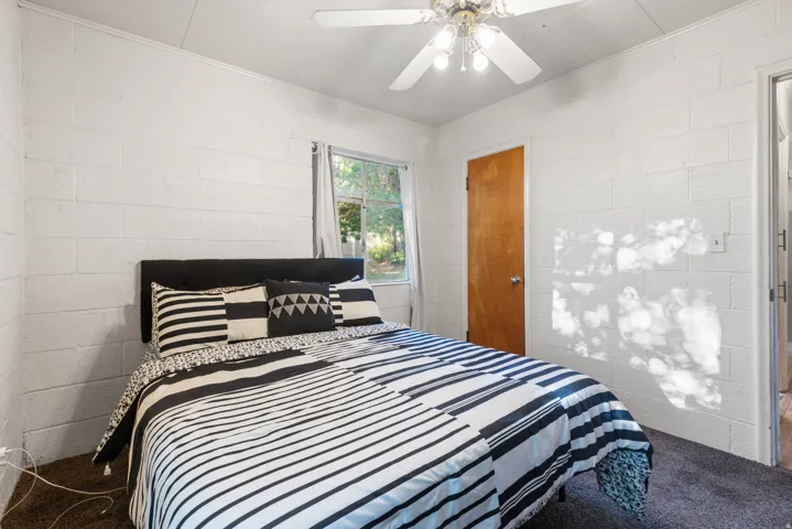 Bedroom featuring textured white block walls, dark carpeting, and a single window offering natural illumination