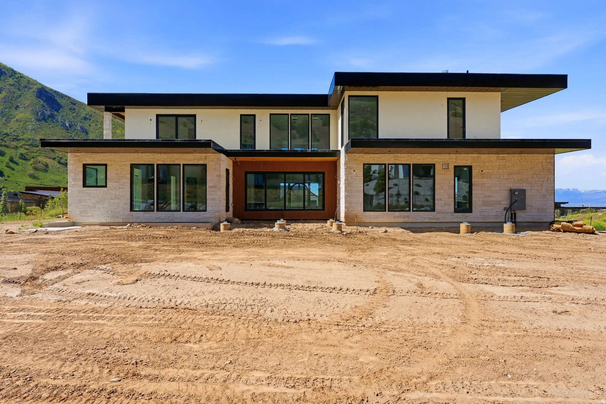 Modern architectural exterior with a flat roofline, white stucco, and stone veneer accents