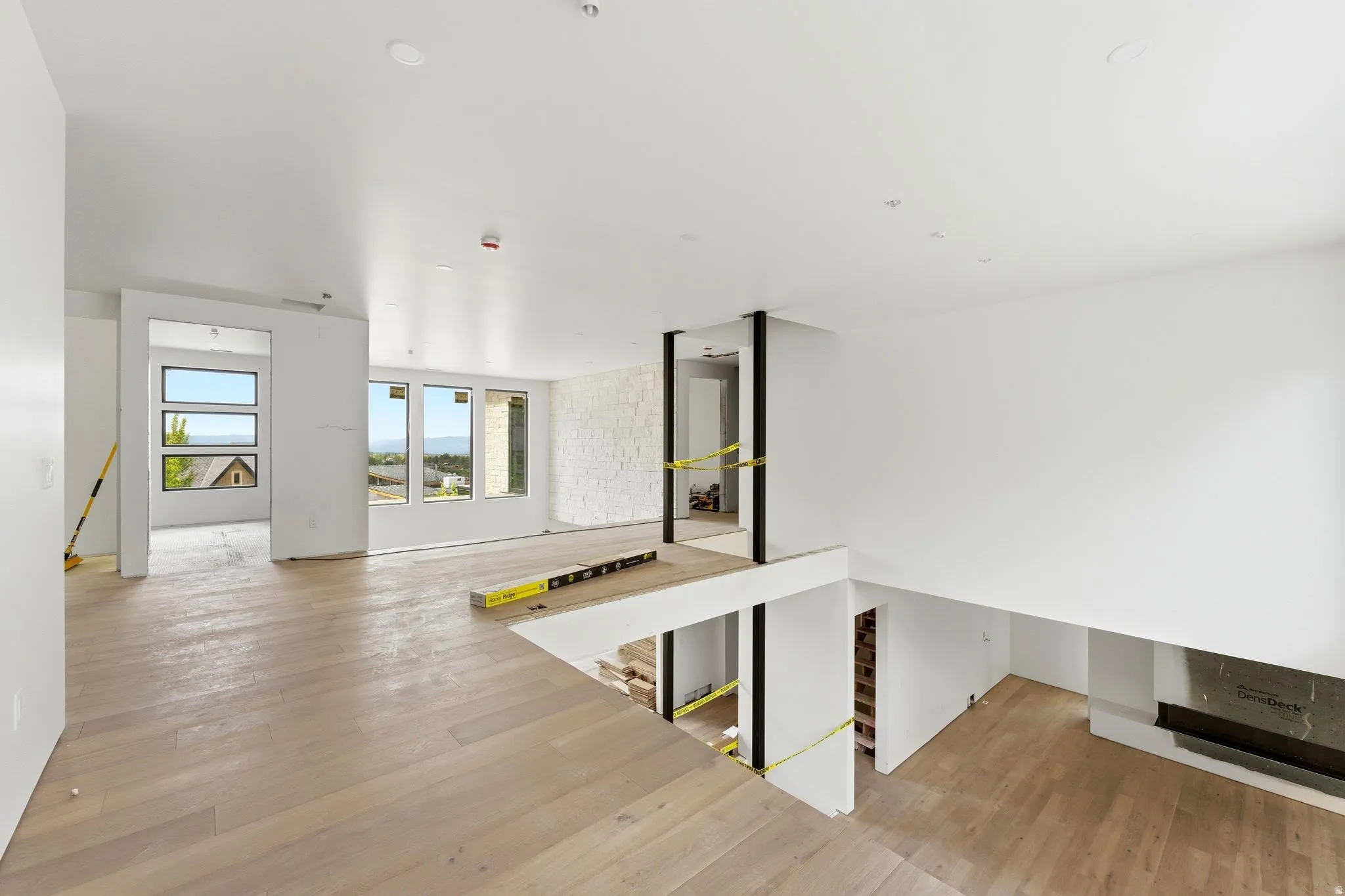 Open-concept interior featuring light wood-finish flooring, recessed lighting, and multiple large windows