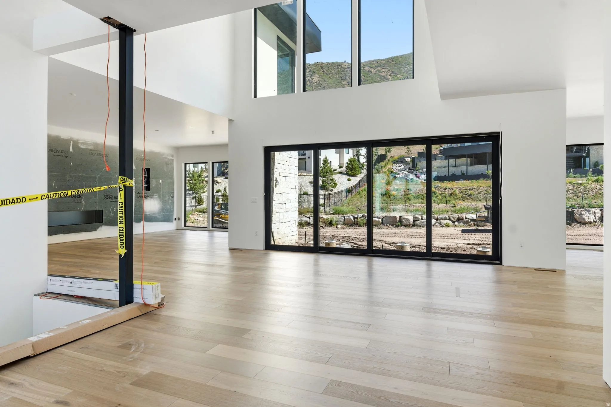 Spacious interior featuring light wood-finish flooring, high ceilings, and a wall of multi-panel sliding glass doors
