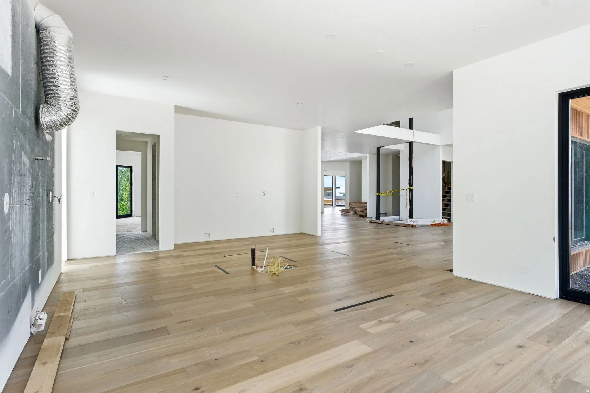 Expansive open-concept interior featuring light wood-finish flooring, white walls, and recessed lighting