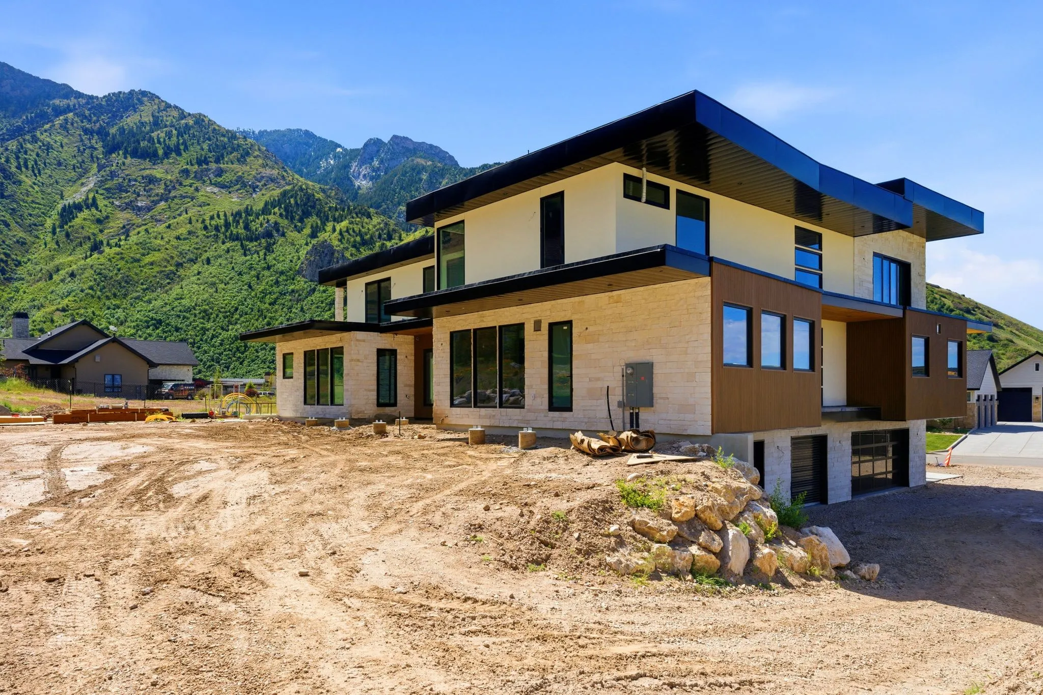 Contemporary multi-level residence featuring a flat roofline, neutral-toned stucco, and stone veneer accents