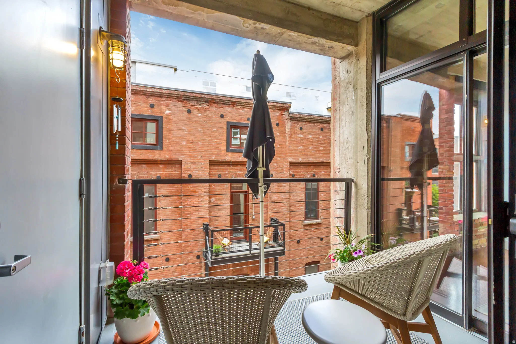 Outdoor balcony featuring a cable railing system, exposed concrete ceiling, and sliding glass door