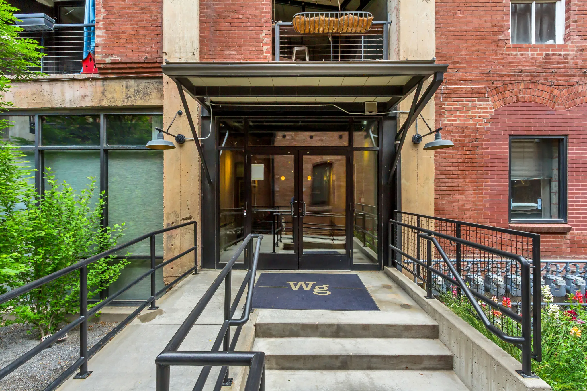 Building entrance featuring a glass door, metal canopy, and exterior sconce lighting