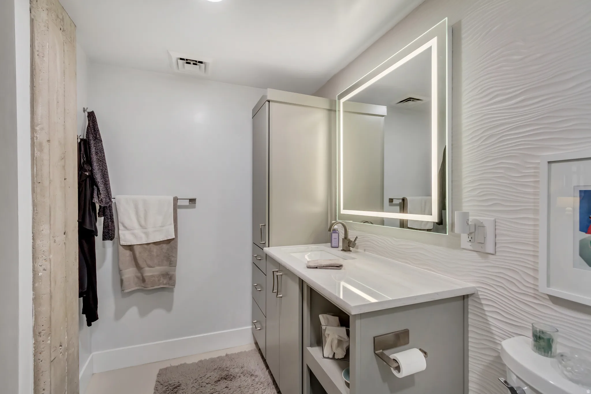 Contemporary bathroom featuring a grey vanity with a white countertop and an integrated sink