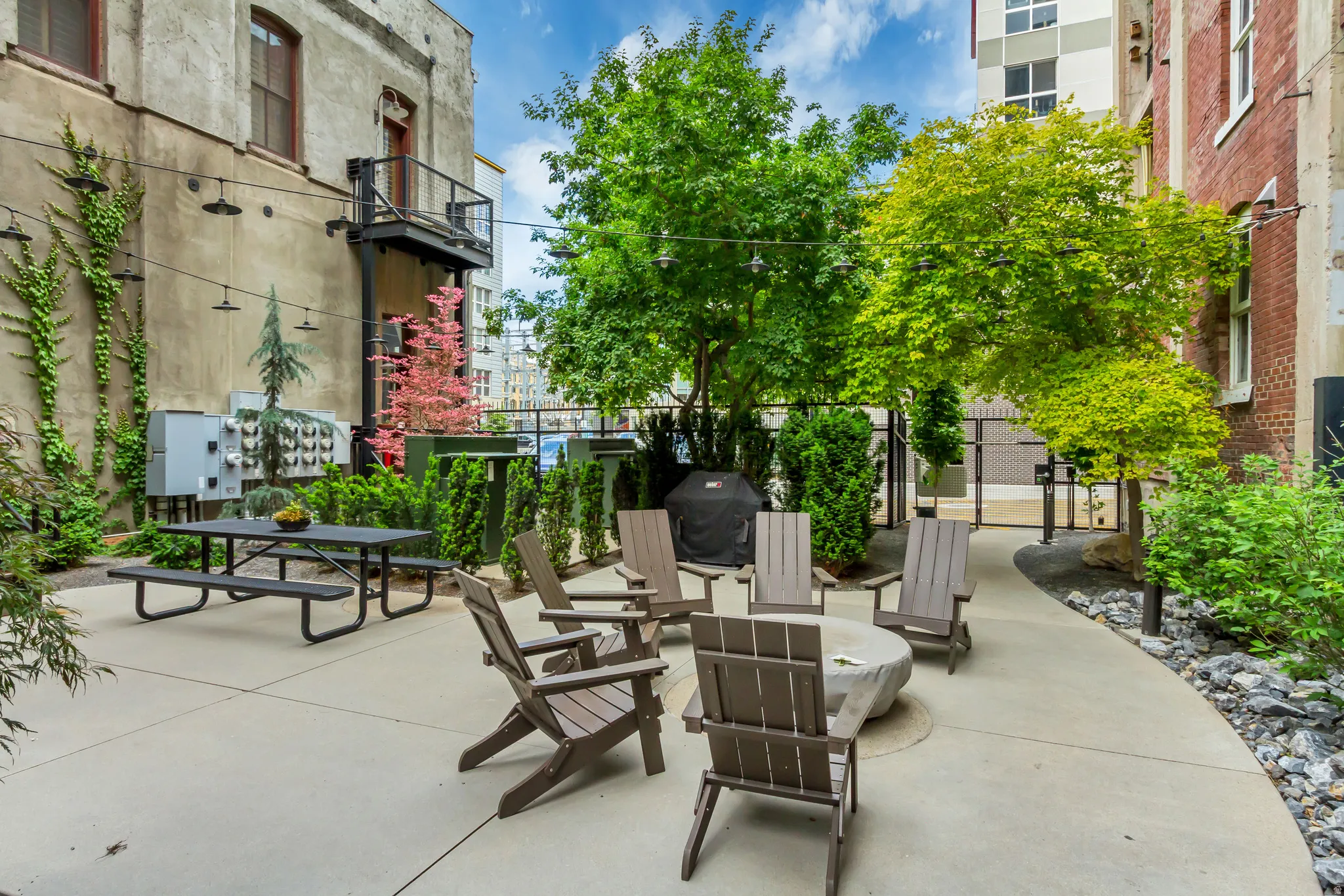 Outdoor courtyard featuring a concrete patio, a central fire pit, and string lighting