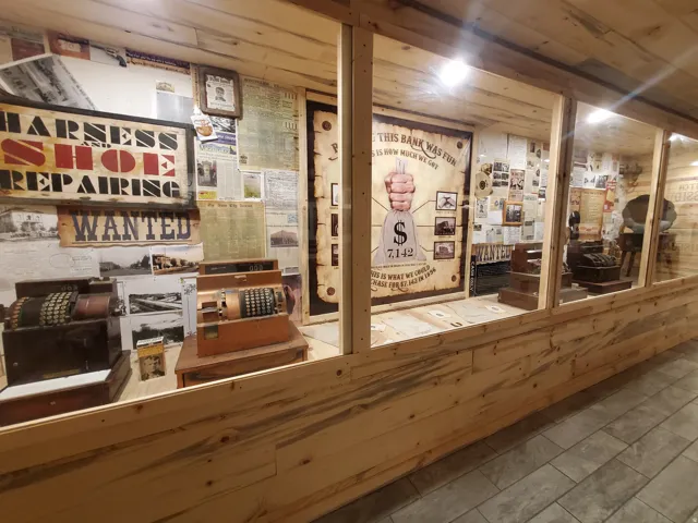 Custom built-in display case with natural wood paneling and glass enclosures, featuring historical ephemera and vintage mechanical cash registers