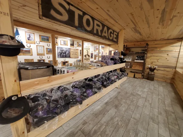 Interior space featuring extensive wood paneling on walls and ceiling, light-toned wood-finish flooring, and a prominent display counter with built-in shelving