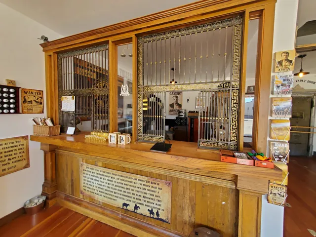 Ornate teller's cage crafted from rich wood-finish materials and detailed metalwork, featuring a counter with paneling below