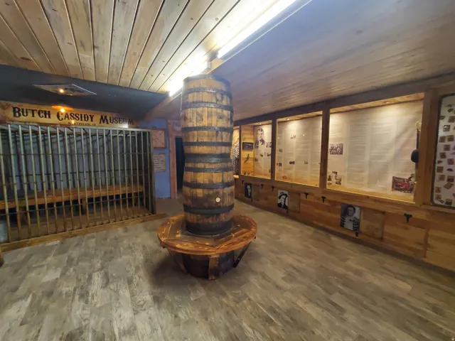 Interior space featuring wood-finish flooring, a prominent decorative barrel, and extensive built-in display cases with lighting