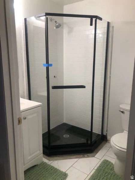 Corner shower enclosure featuring black framing and a black shower pan