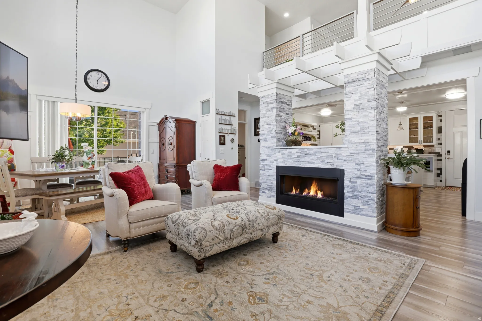 Living space featuring a stacked stone fireplace with a black surround, light wood-finish flooring, and a two-story ceiling
