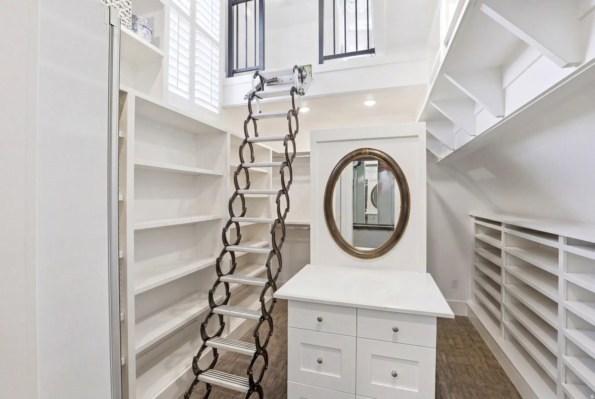 Custom-built closet system featuring extensive shelving, built-in drawer storage, and an oval mirror
