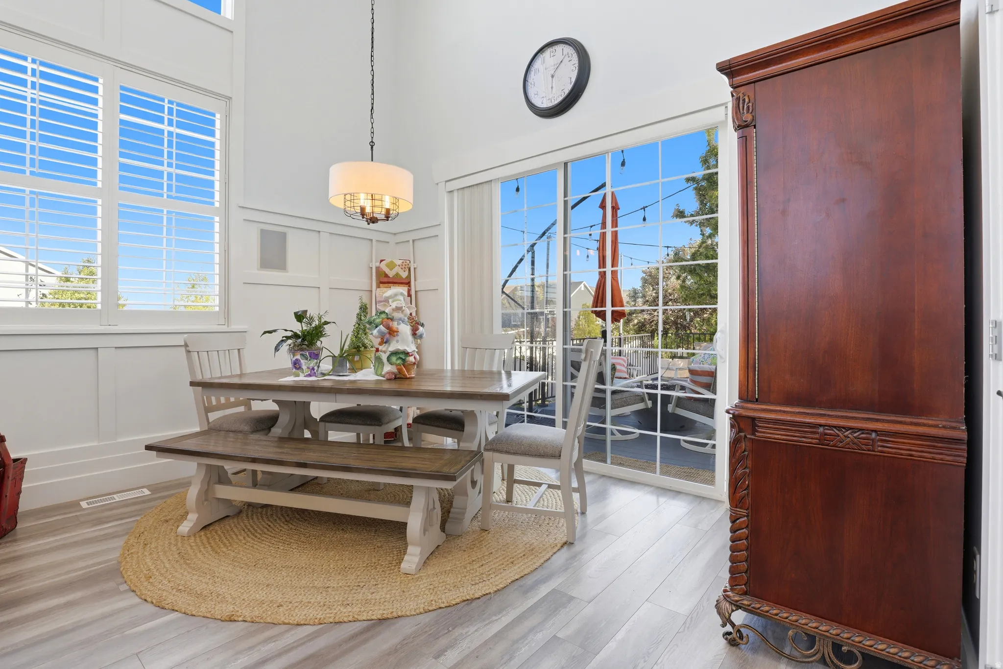 Dining area featuring high ceilings, white wainscoting, and large windows with plantation shutters