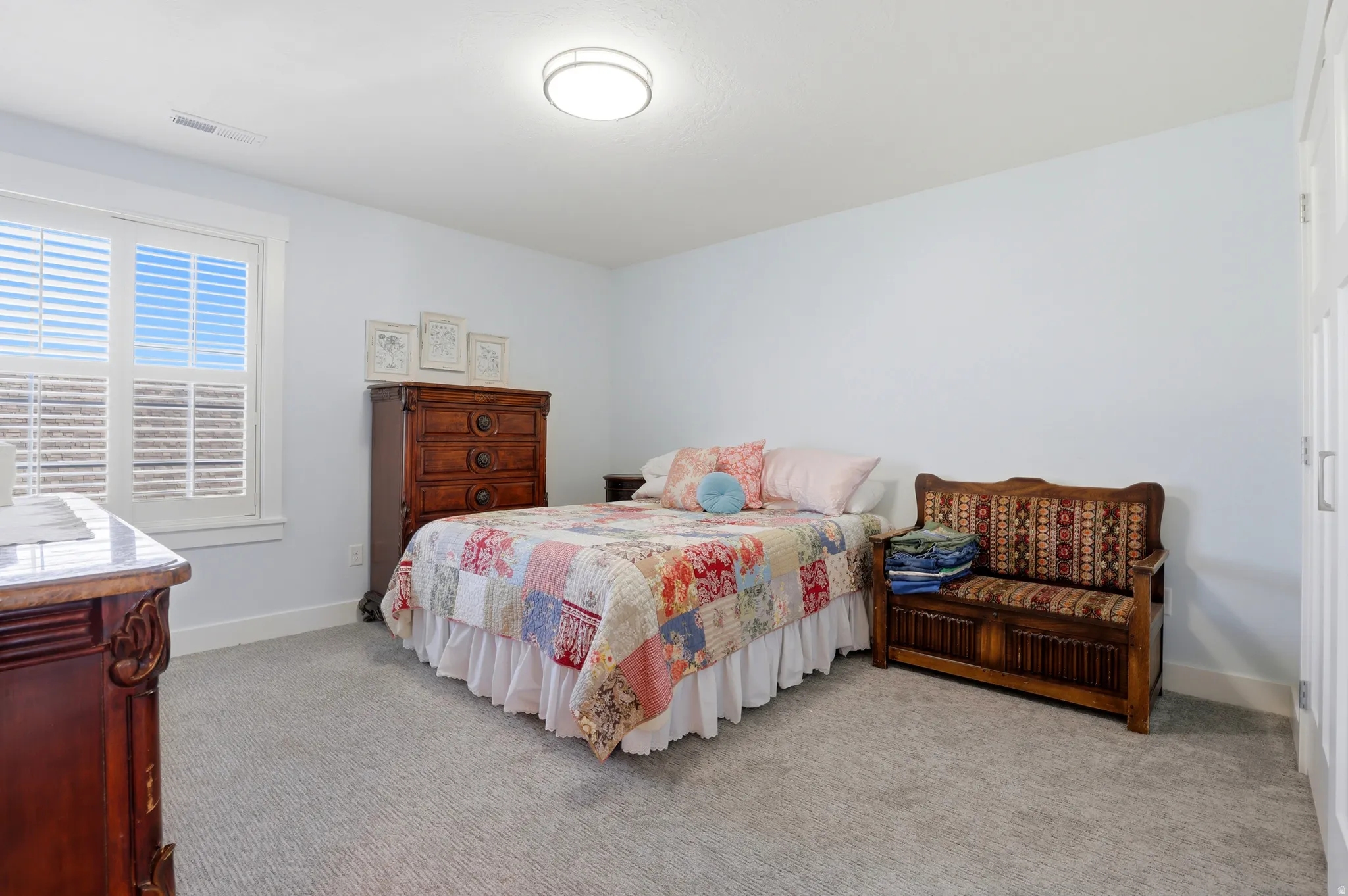 Carpeted room featuring a double window with white plantation shutters, light blue walls, a flush-mount ceiling light fixture, and white trim