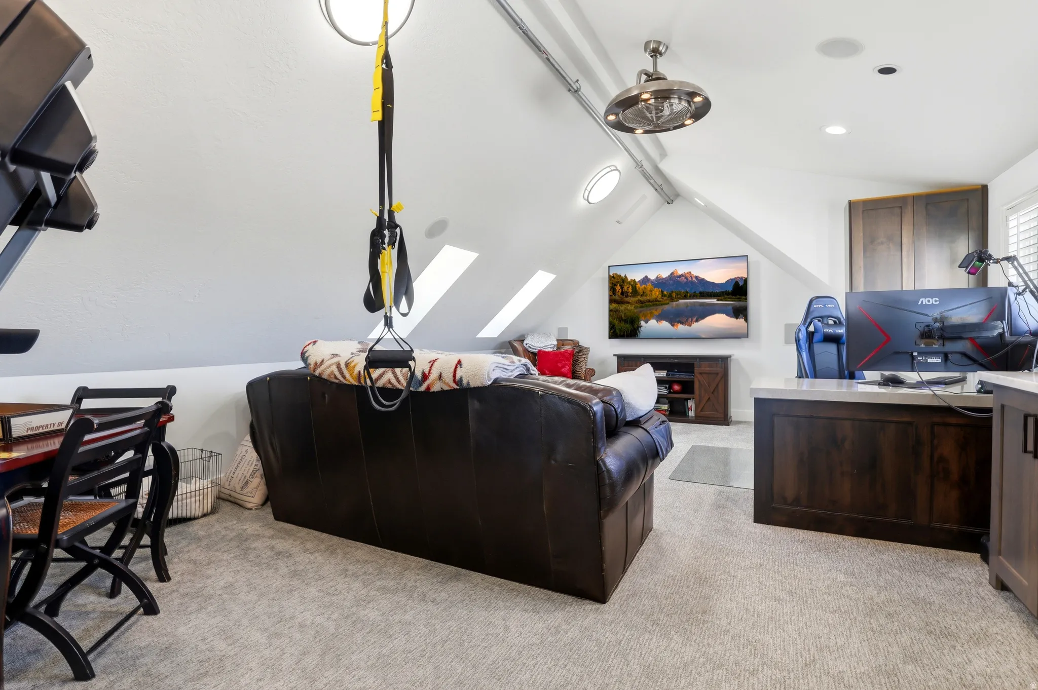 Attic space featuring sloped ceilings, multiple skylights, recessed lighting, and a brushed nickel ceiling fan