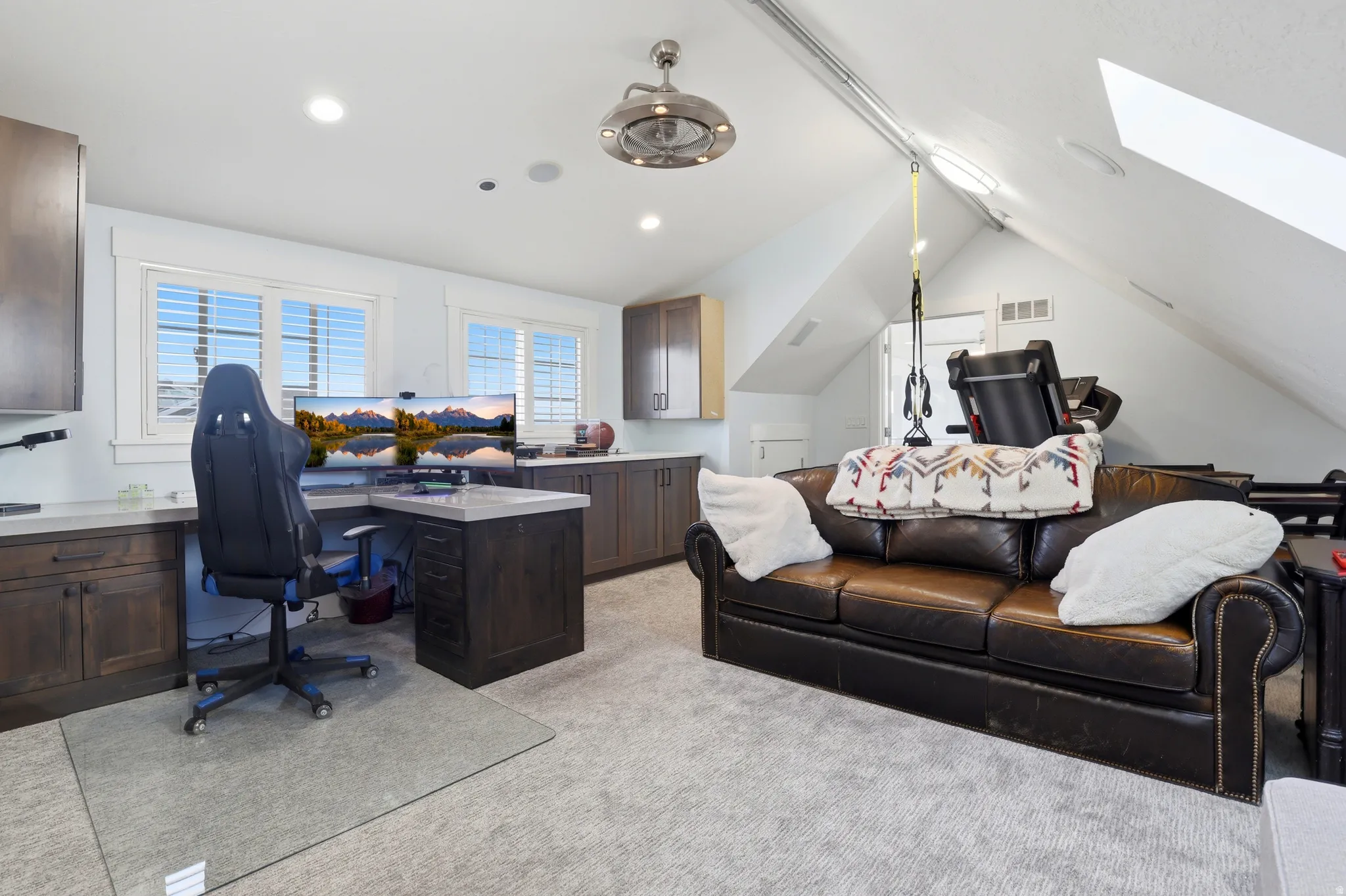 Versatile bonus room featuring wood-finish cabinetry, light-toned countertops, and multiple windows with plantation shutters