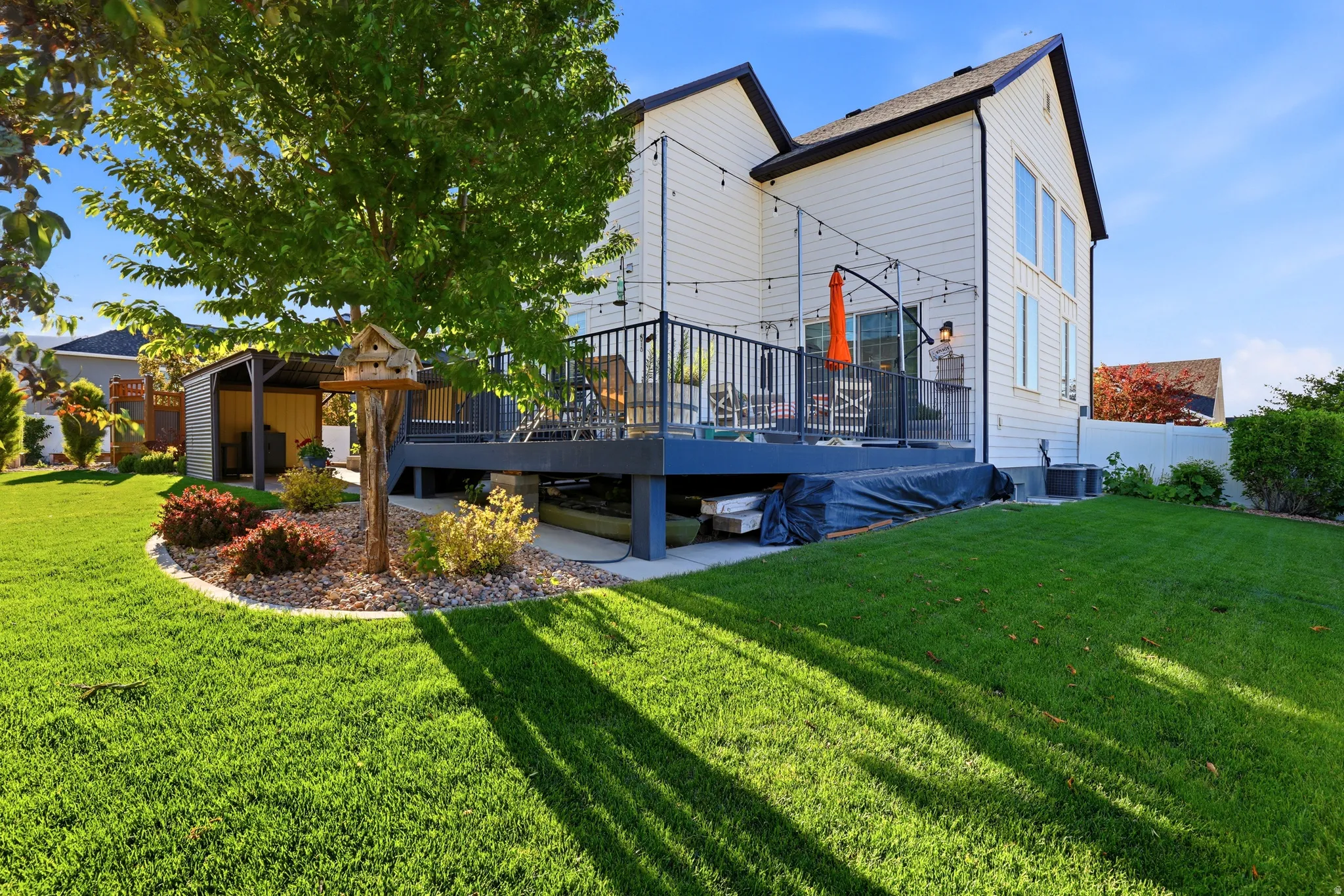 Spacious backyard featuring a multi-level deck, manicured lawn, and mature tree