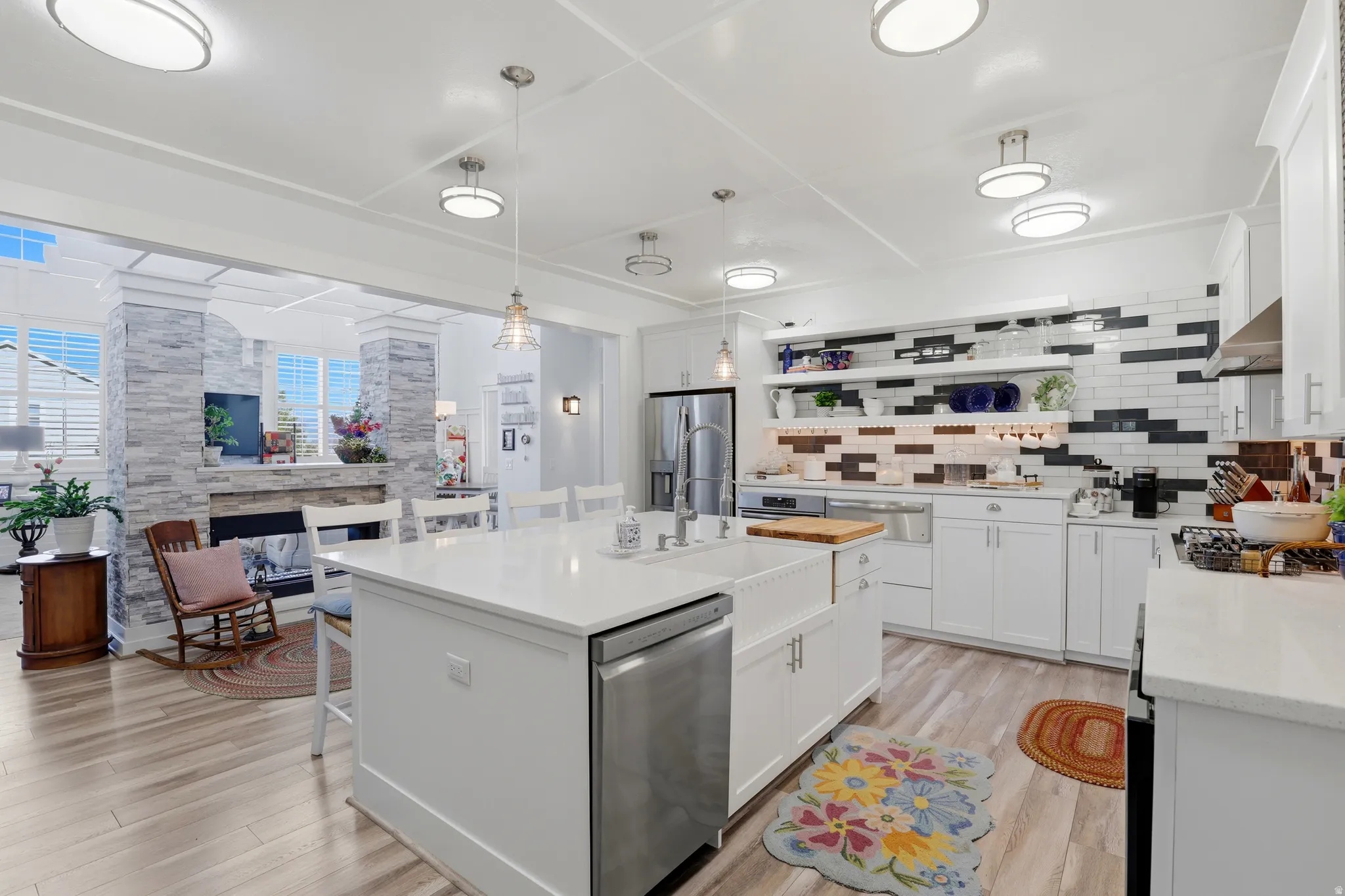 Kitchen featuring a center island with a farmhouse sink, stainless steel dishwasher, and quartz countertop