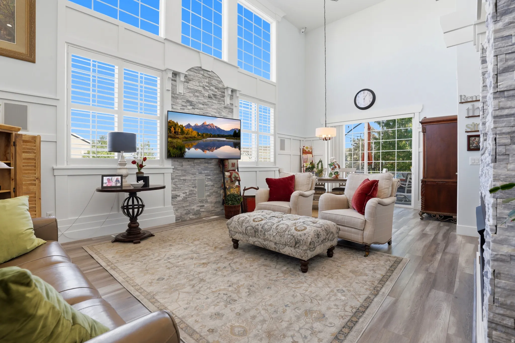 Two-story living area featuring high ceilings, light wood-finish flooring, and a stone-clad accent wall