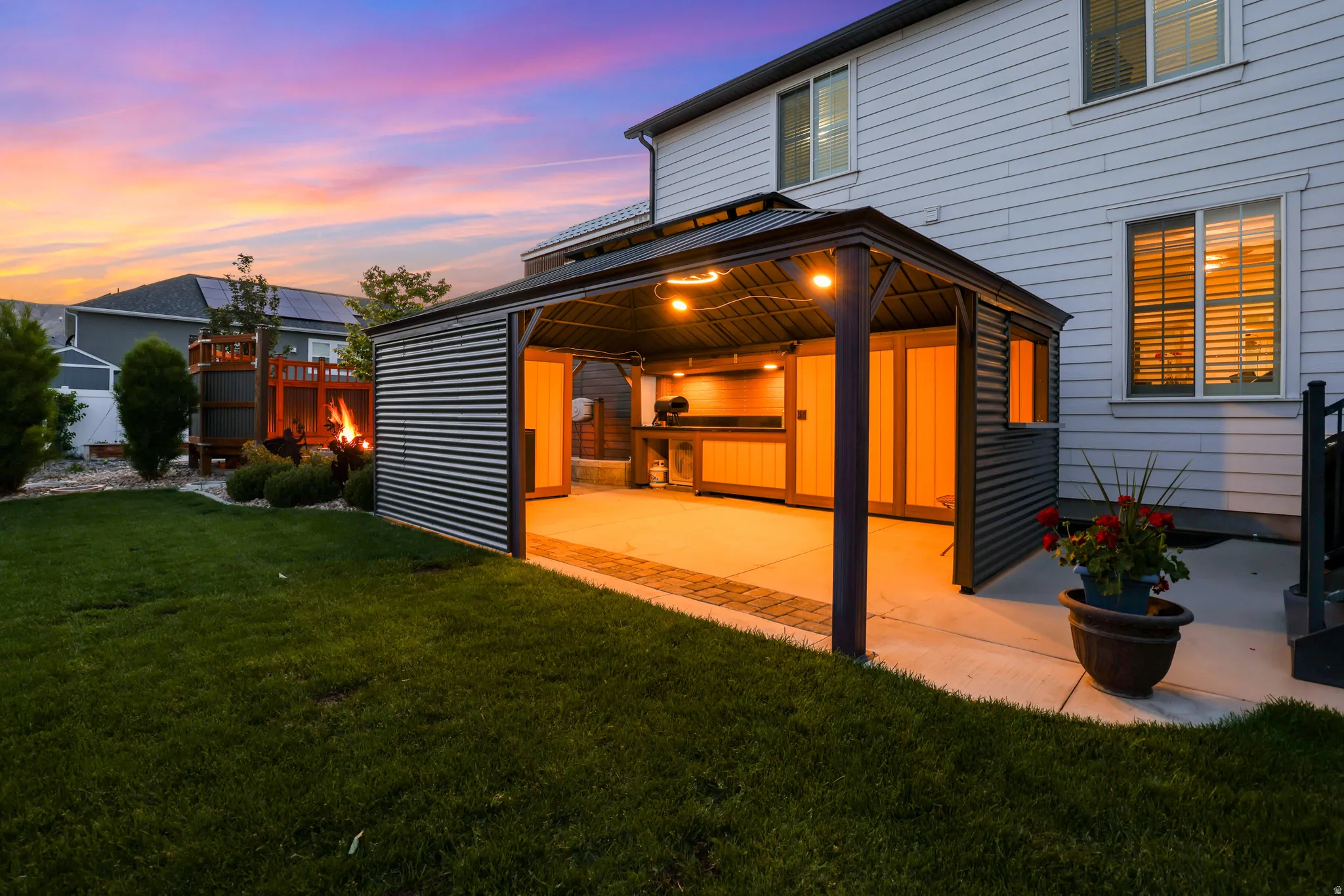 Exterior entertainment area featuring a covered patio with string lighting, built-in cabinetry, and a concrete slab