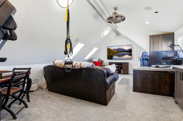 Attic space featuring sloped ceilings, multiple skylights, recessed lighting, and a brushed nickel ceiling fan