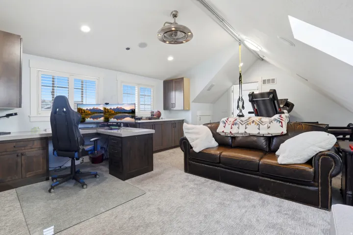 Versatile bonus room featuring wood-finish cabinetry, light-toned countertops, and multiple windows with plantation shutters