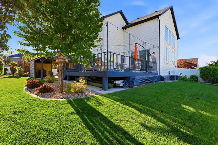 Spacious backyard featuring a multi-level deck, manicured lawn, and mature tree
