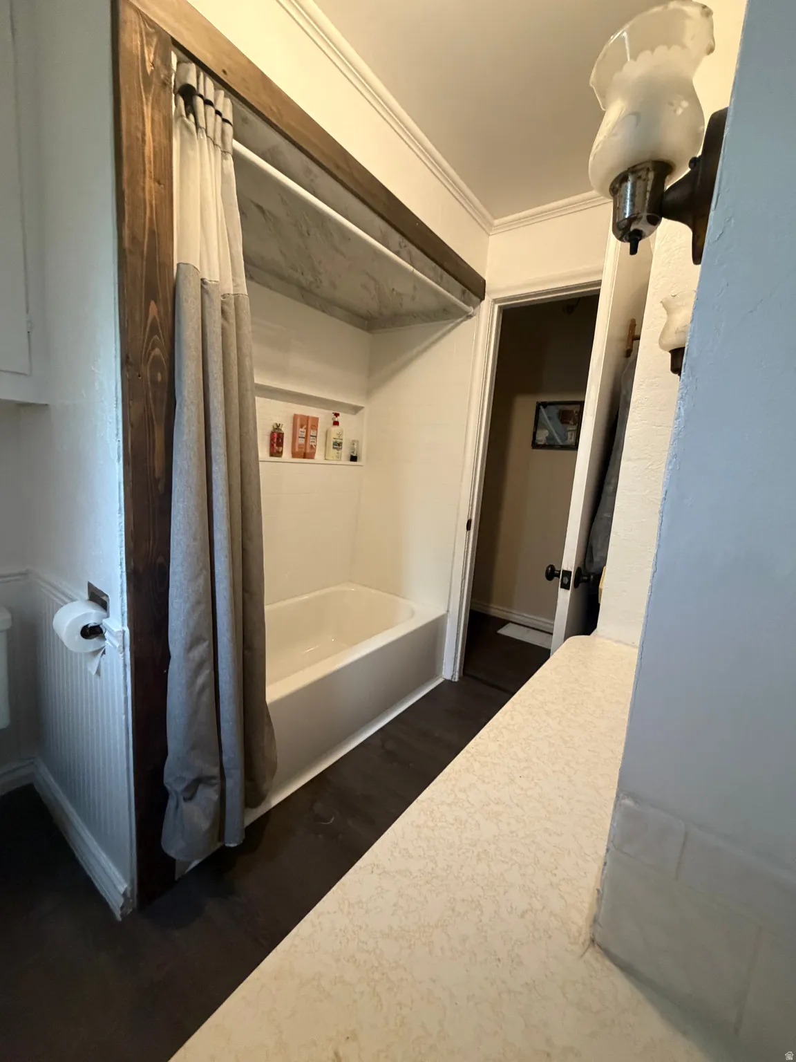 Bathroom featuring a white bathtub, built-in shower niche, dark wood-finish flooring, and a textured countertop
