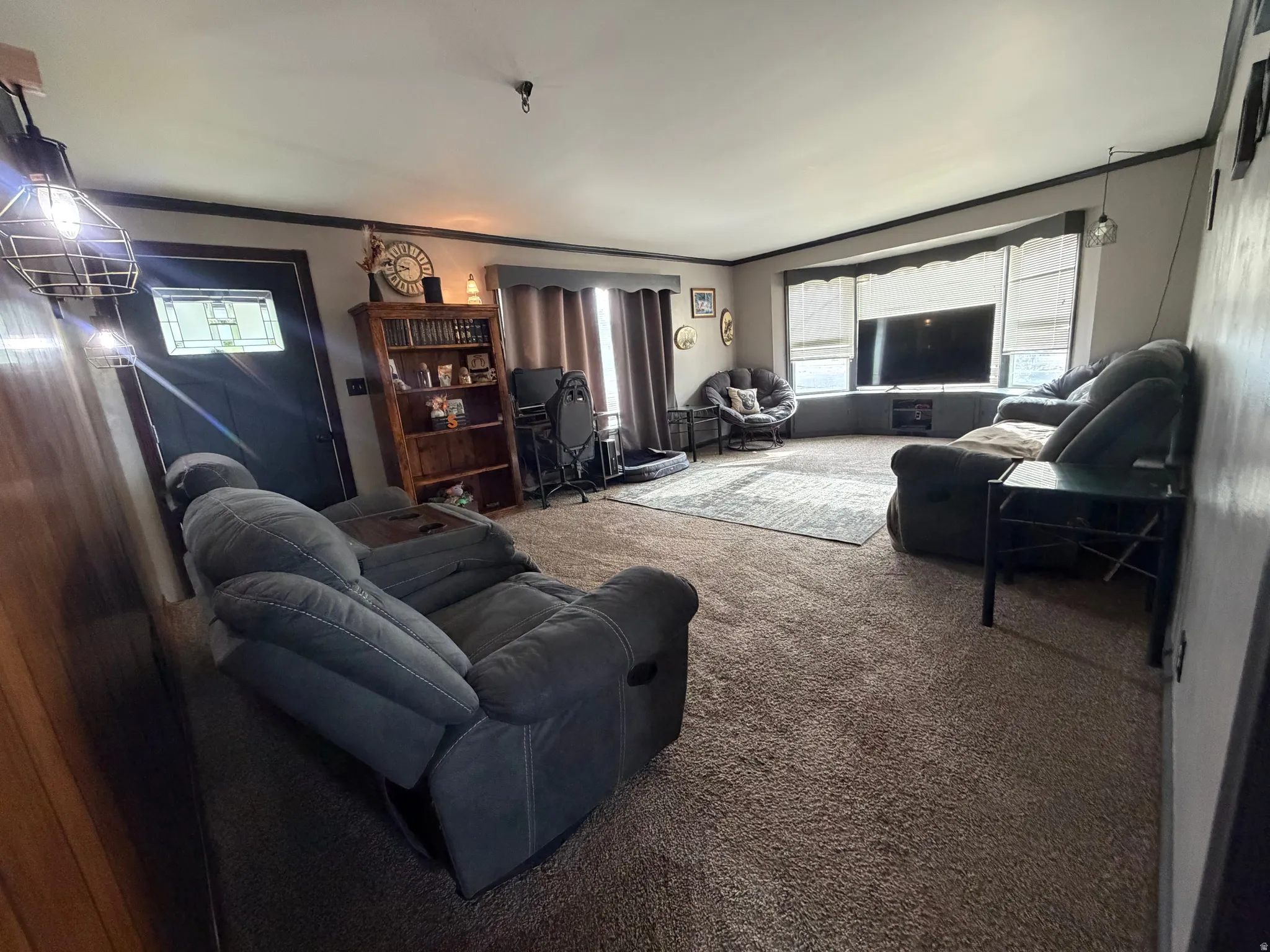 Carpeted living area featuring a bay window with a built-in media console, dark trim accents, and a front entry door with a decorative glass insert