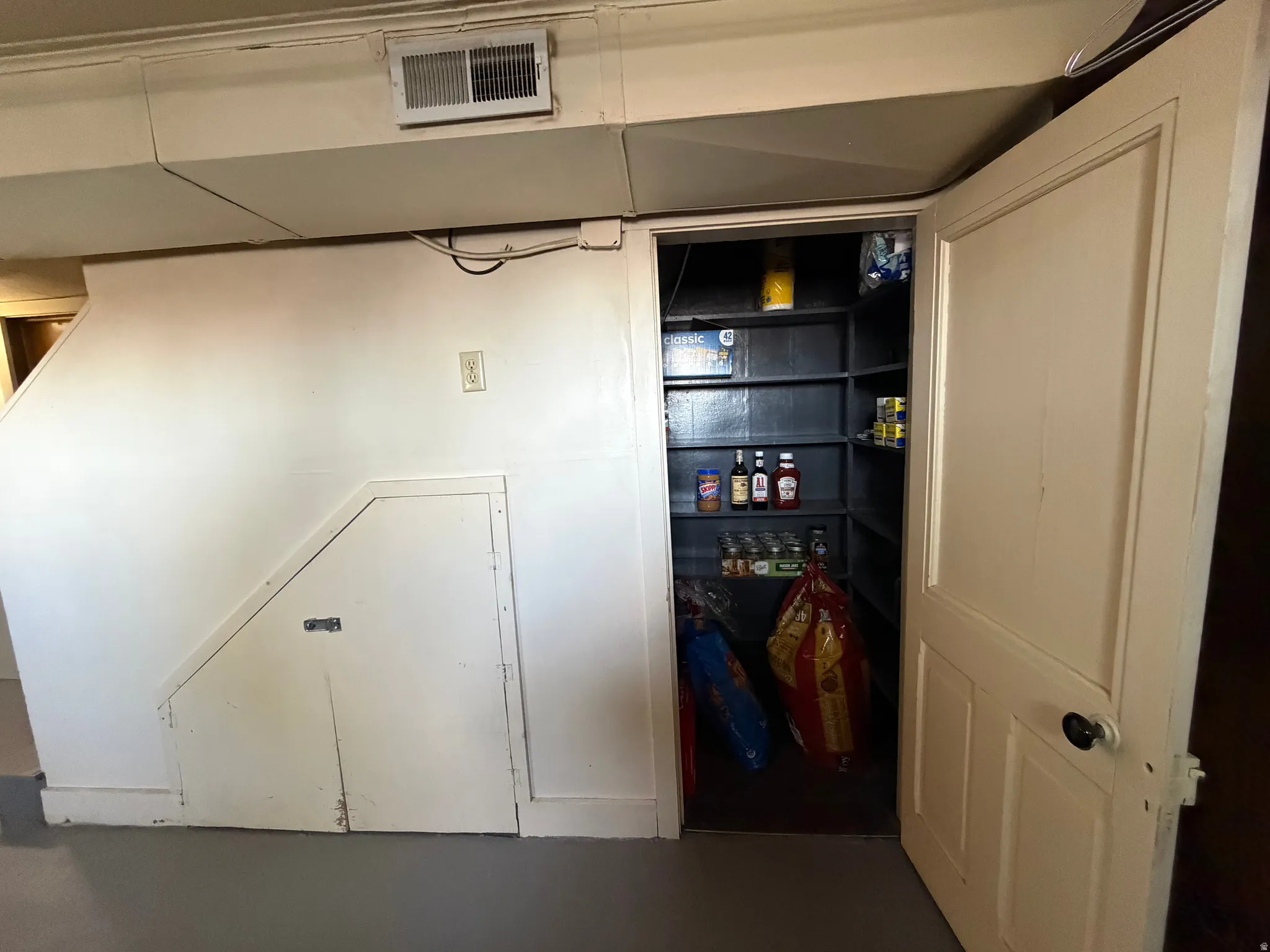 Storage pantry featuring built-in shelving, a solid panel door, and a black doorknob