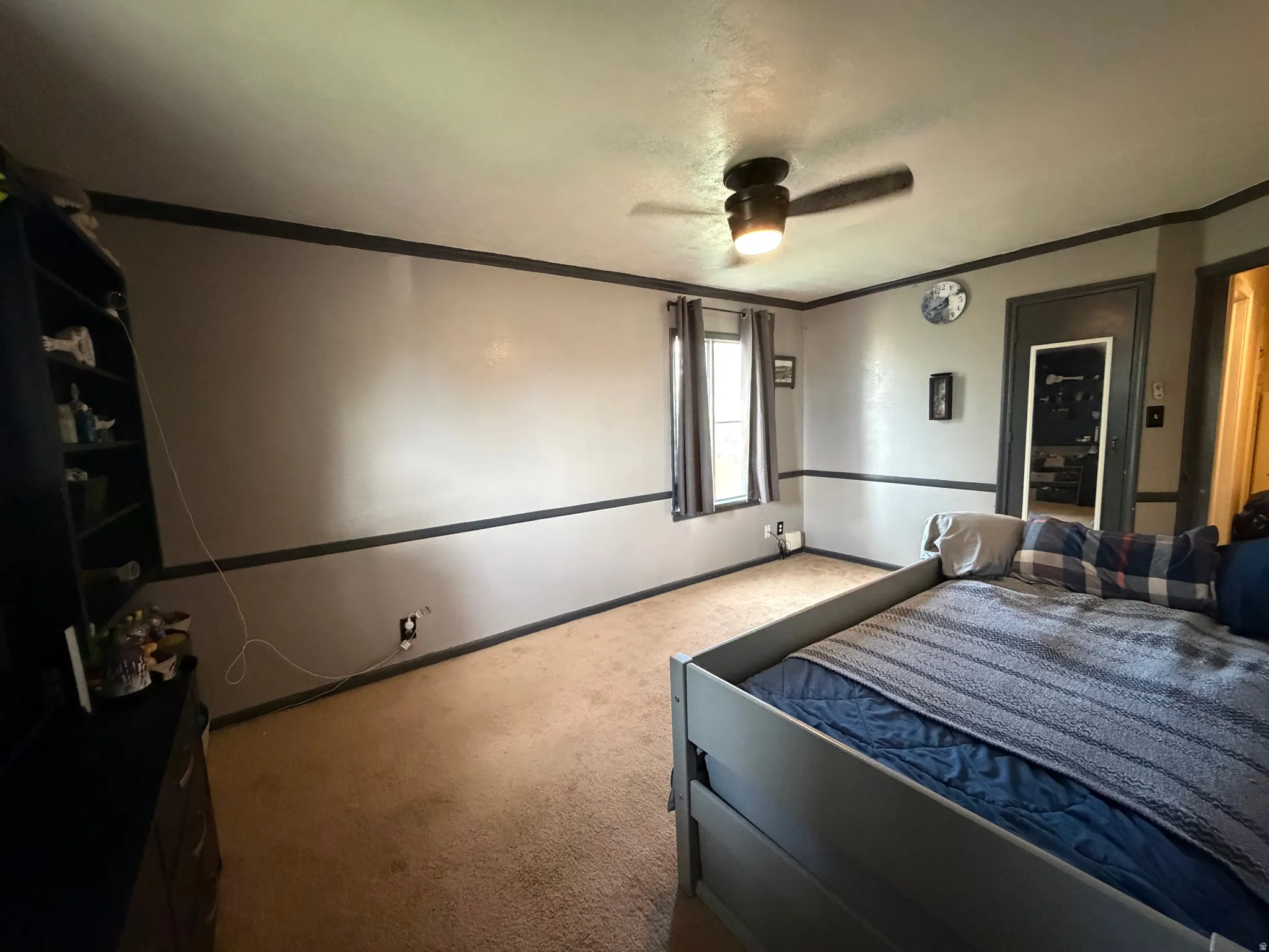 Carpeted room featuring a ceiling fan with integrated lighting, a window with drapery, and a two-tone wall finish with dark trim