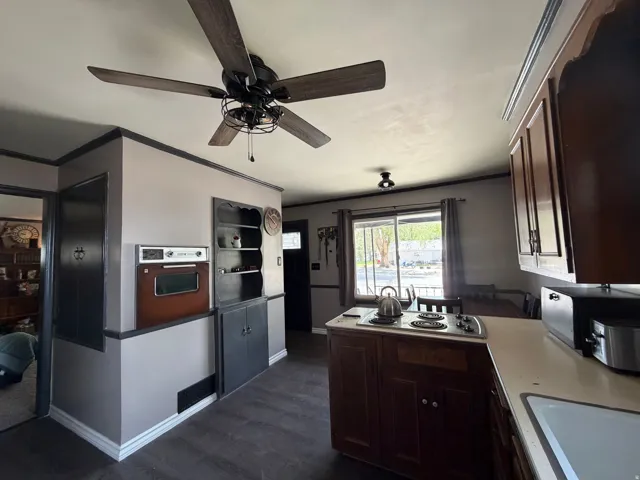 Kitchen featuring a ceiling fan, built-in oven, built-in shelving, wood-finish flooring, and slider door
