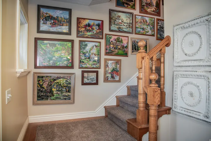 Staircase featuring oak wood balusters and handrail, carpeted steps, and white baseboards