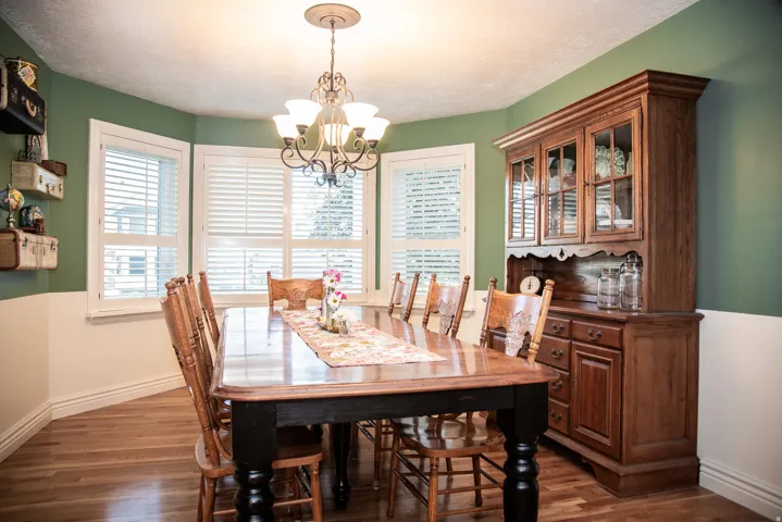 Dining area featuring wood flooring and a bay window with white plantation shutters