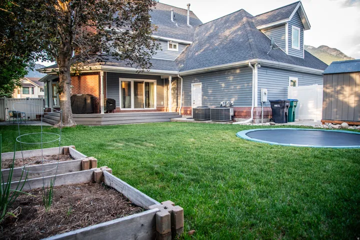 Expansive green lawn with raised garden beds and a large in-ground circular trampoline
