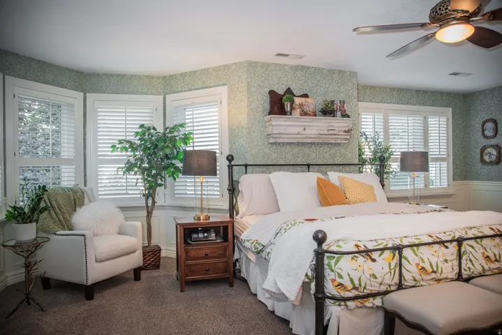 Huge primary bedroom featuring a bay window with plantation shutters