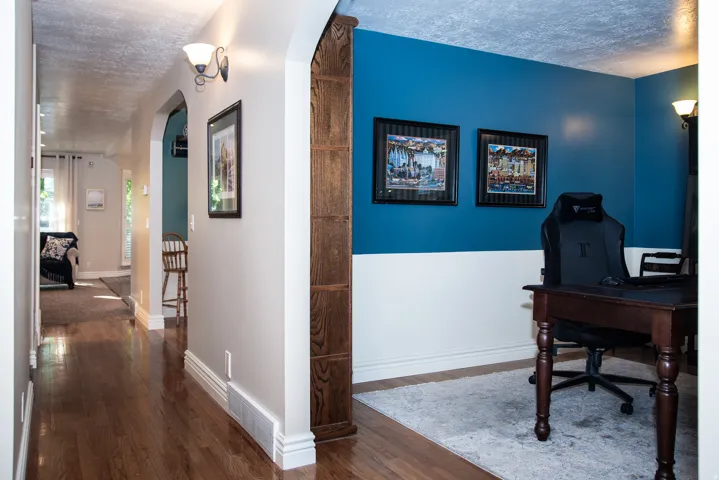 Hardwood flooring extending through an arched entryway into formal living room or office space