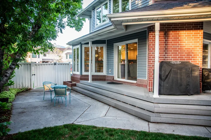 Wrap-around composite porch with wide steps, a concrete patio, and a privacy fence
