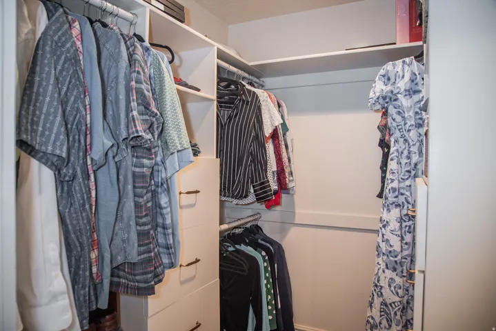 Custom closet organization system featuring multiple hanging rods, built-in shelving, and integrated drawers
