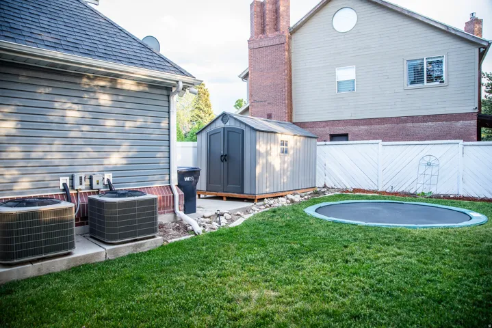 Manicured lawn area featuring a white privacy fence and a storage shed
