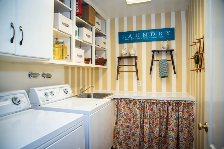 Dedicated laundry area featuring a utility sink, open shelving, and laundry chute concealed behind cupboard door