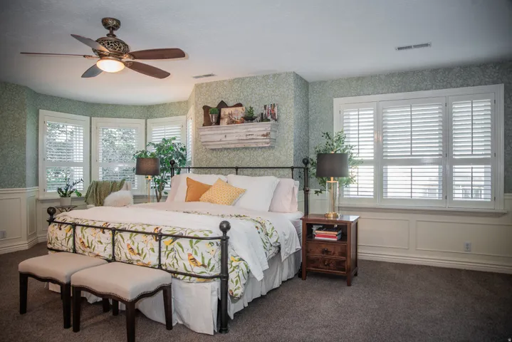 Primary bedroom featuring picture-frame molding, multiple windows with plantation shutters