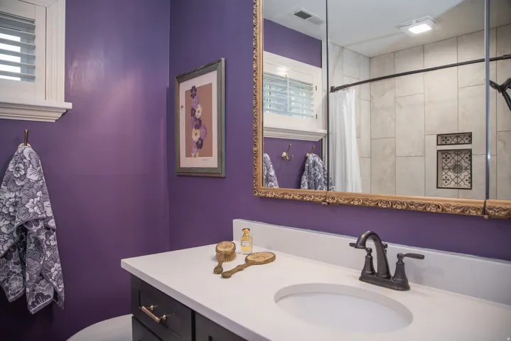 Bathroom vanity featuring a dark wood-finish cabinet with gold-tone hardware, a quartz countertop with an integrated sink, and a bronze-finish faucet
