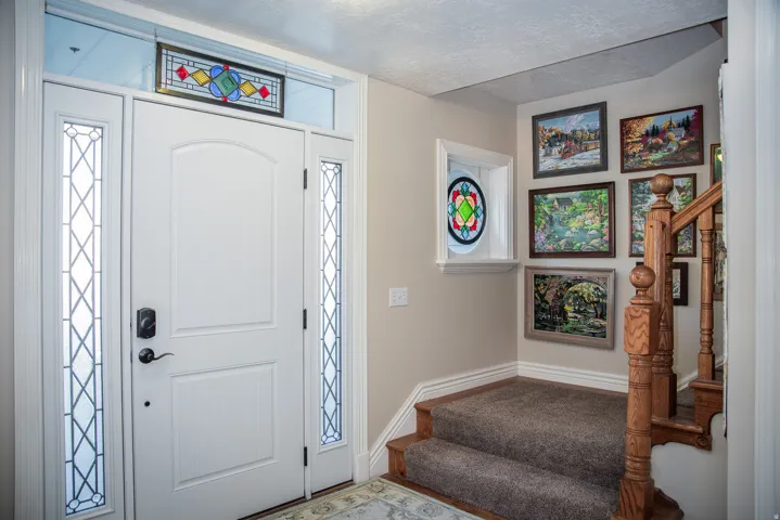 Entryway featuring a white paneled front door with decorative glass sidelights and transom