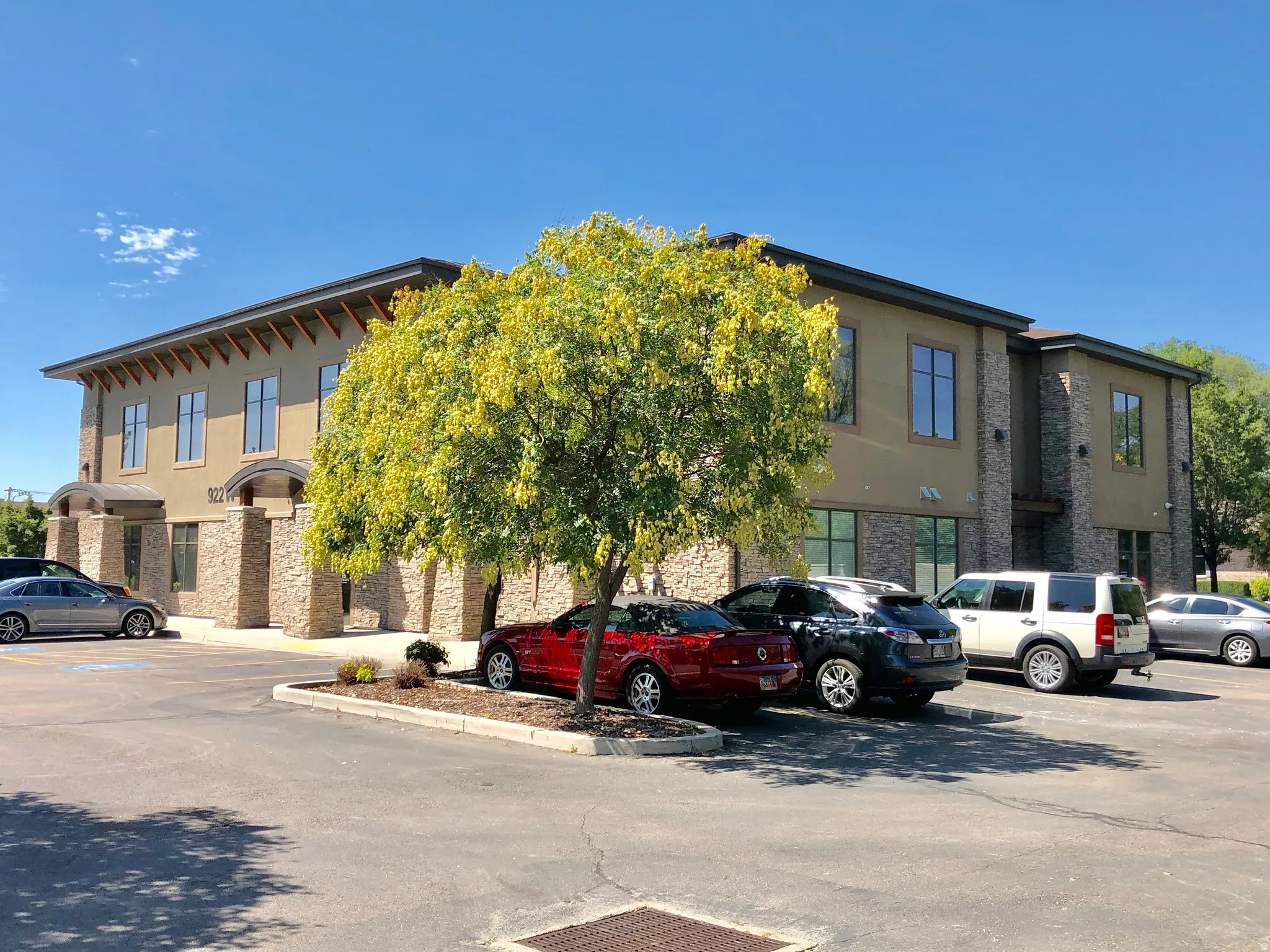 Commercial building featuring a stucco exterior, stone facade accents, large windows, and an asphalt parking lot