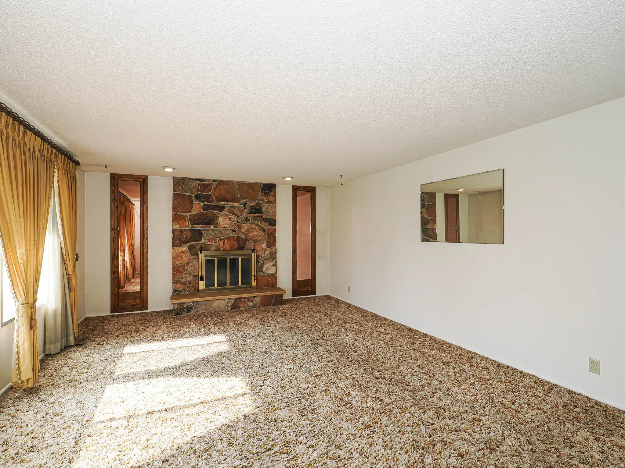 Living area featuring a stone fireplace with a raised hearth, recessed lighting, and wall-to-wall carpeting