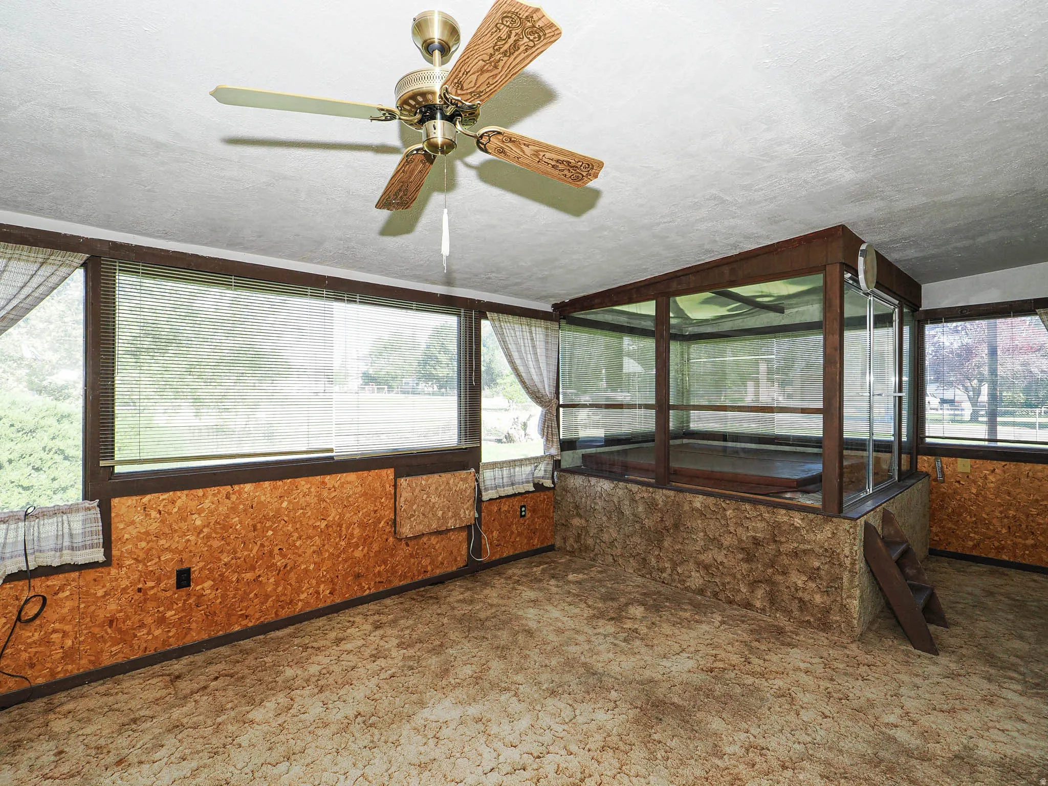 Indoor spa enclosure with glass surround, wood-finish framing, and a built-in step ladder